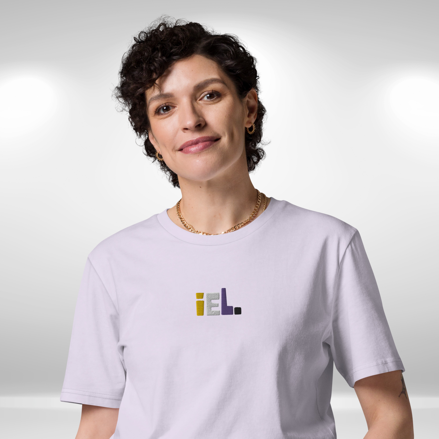Model wearing a lavender t-shirt featuring the french pronoun iel embroidery centre chest. 