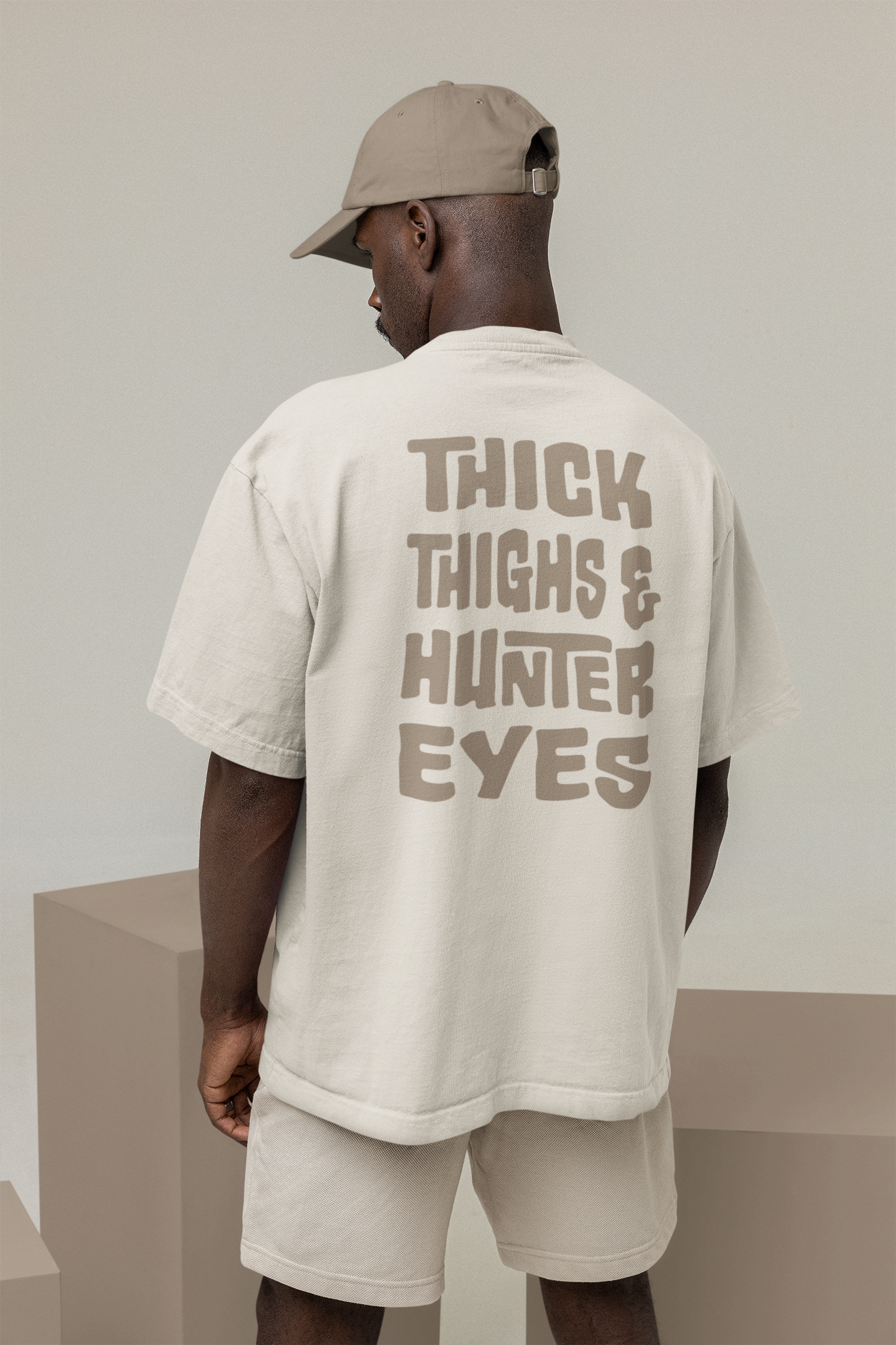 Oversized faded bone T-shirt featuring a bold back graphic with the text: "Thick thighs & hunter eyes."