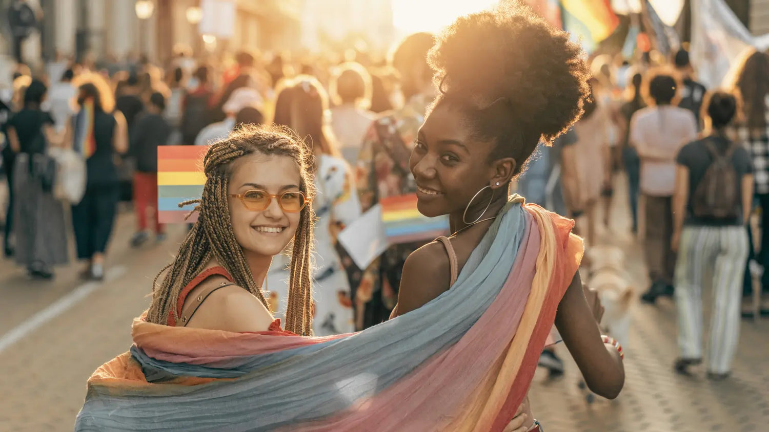 Two girls proudly marching through the city, wrapped in a pride flag, spreading love and acceptance