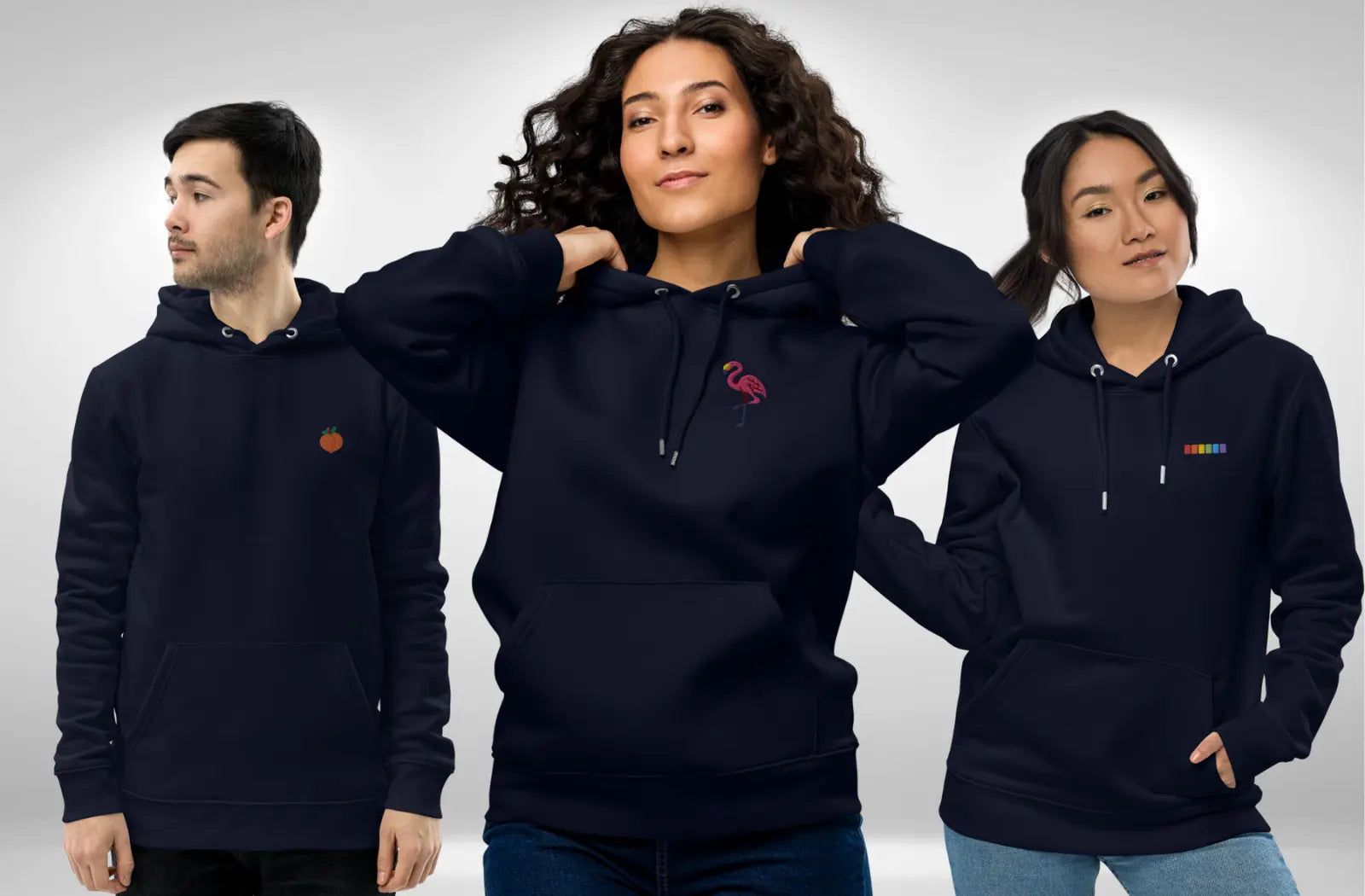 Three people wearing navy blue eco-friendly hoodies, each with subtle queer designs embroidered on the left chest