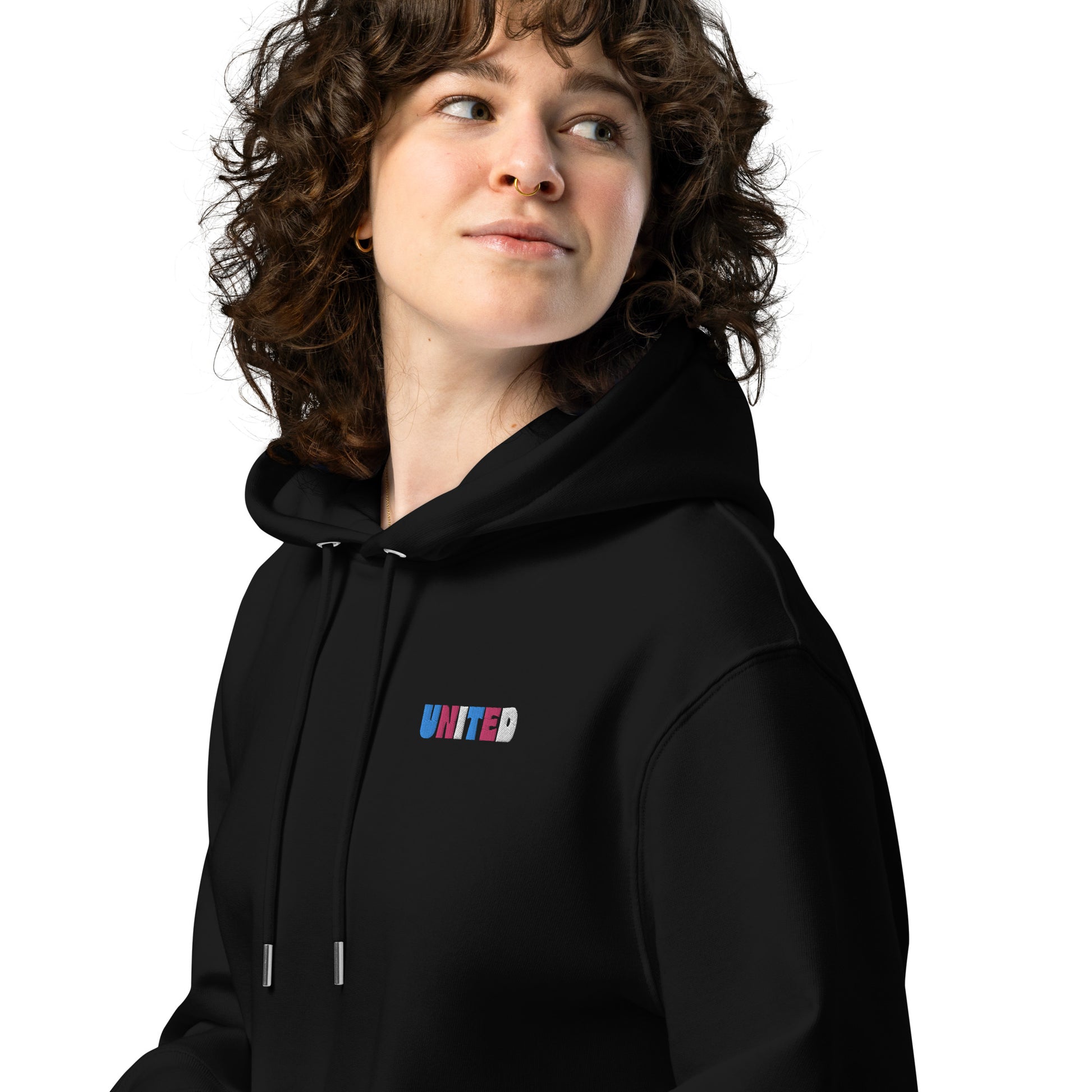 A female model wearing our unisex eco-friendly black hoodie featuring on the upper left chest; united embroidery in transgender pride colors, adding a touch of lgbtq to your outfit. sizes: small, medium, large, extra large, double extra large.