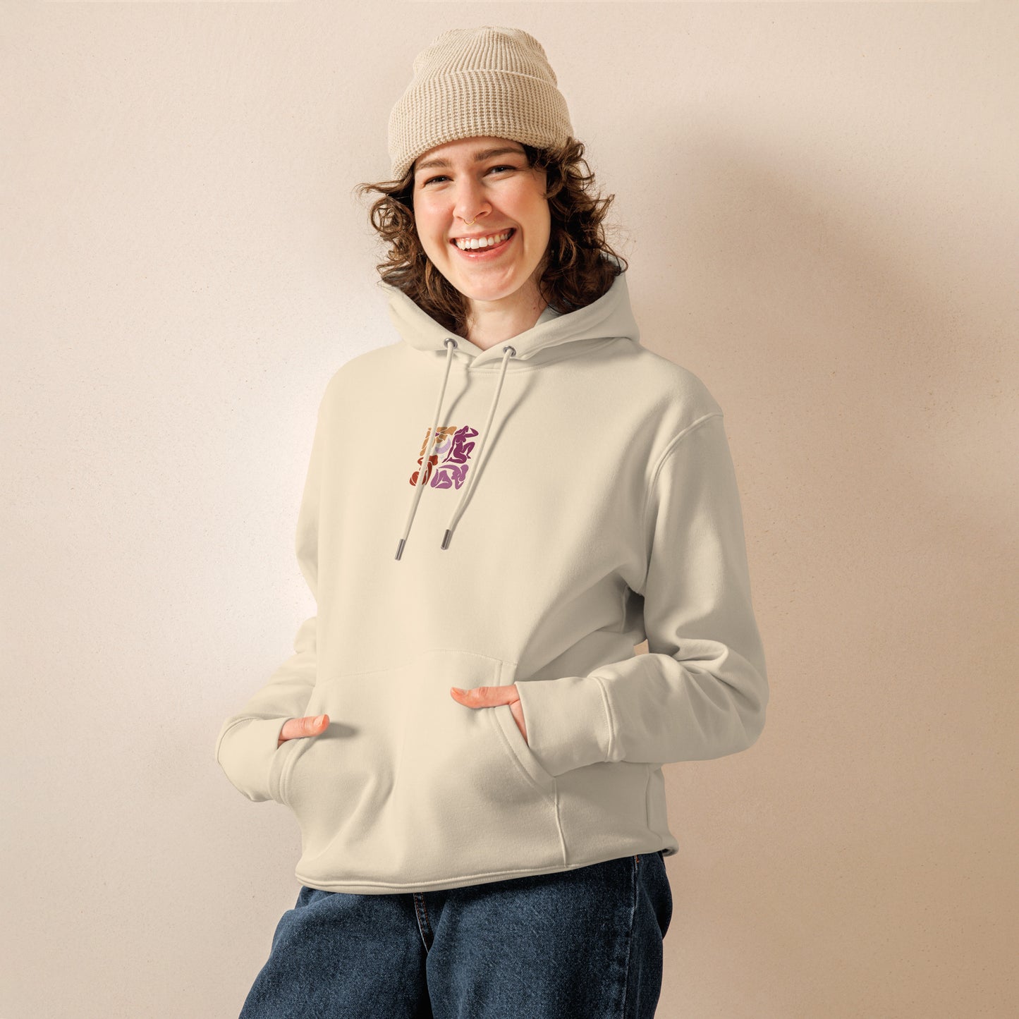 A female model wearing our unisex eco-friendly desert dust hoodie featuring an embroidered Matisse mosaic-inspired design centered chest in lesbian colors, with the same design printed large on the back - adding a touch of lgbtq to your outfit. sizes: small, medium, large, extra large, double extra large.