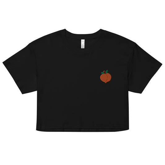 A relaxed, modest black crop top features a subtle peach emoji embroidery. Adding a touch of mischief to your look—a playful celebration of lgbtq culture! Made from 100% combed cotton. Available in Extra Small, Small, Medium, Large, Extra Large.