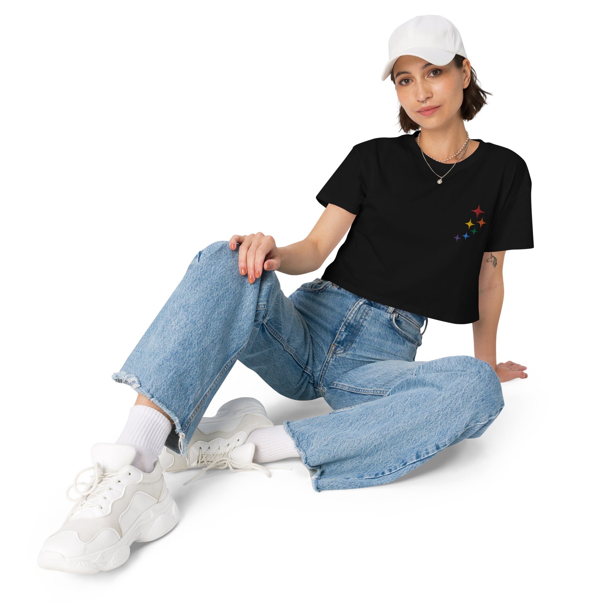 A female model wearing a relaxed, modest black crop top features a subtle rainbow stars embroidery. Adding a touch of rainbow to your look—a playful celebration of lgbtq culture! Made from 100% combed cotton. Available in Extra Small, Small, Medium, Large, Extra Large.