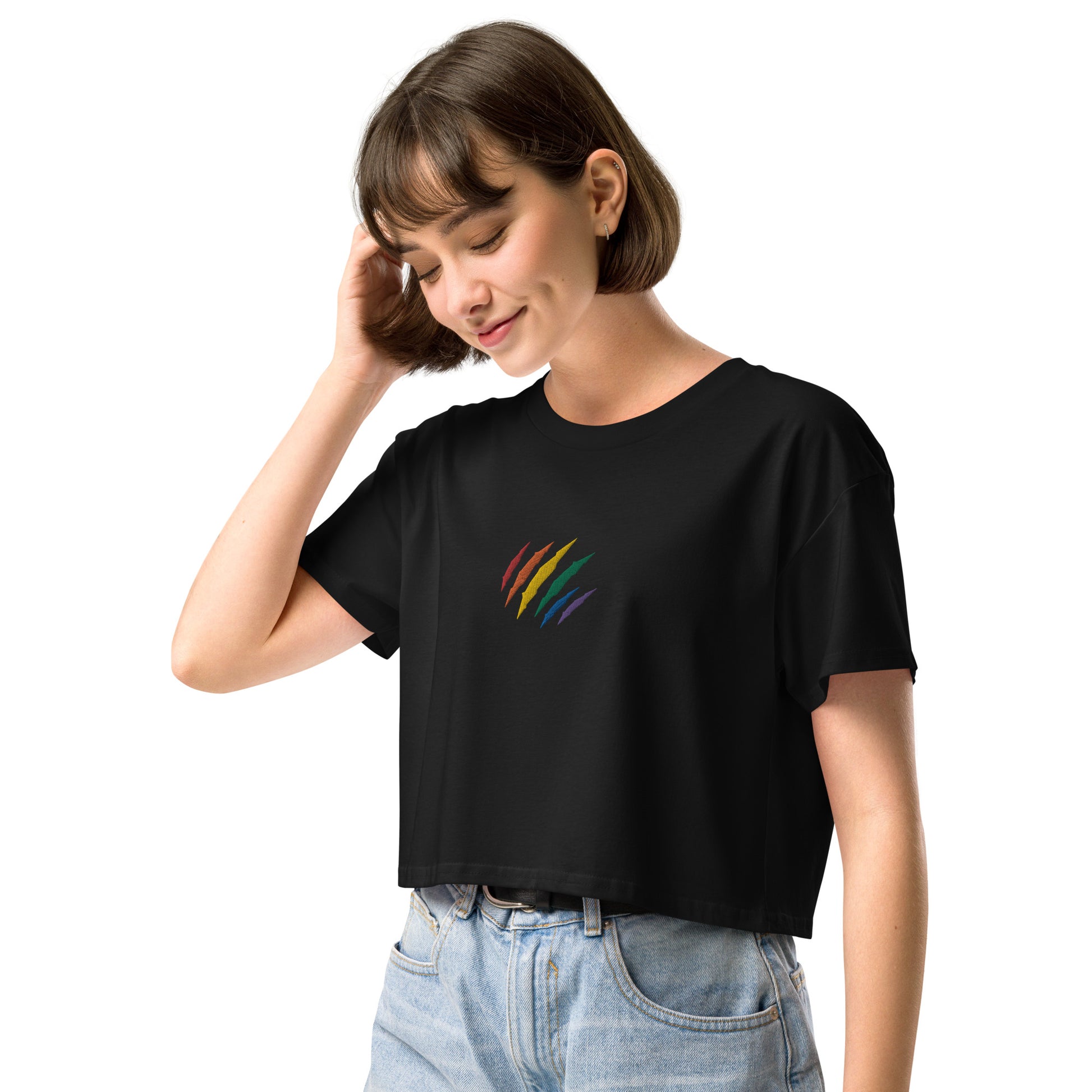 A female model wearing a relaxed, modest black crop top features a subtle rainbow mark embroidery. Adding a touch of rainbow to your look—a playful celebration of lgbtq culture! Made from 100% combed cotton. Available in Extra Small, Small, Medium, Large, Extra Large.