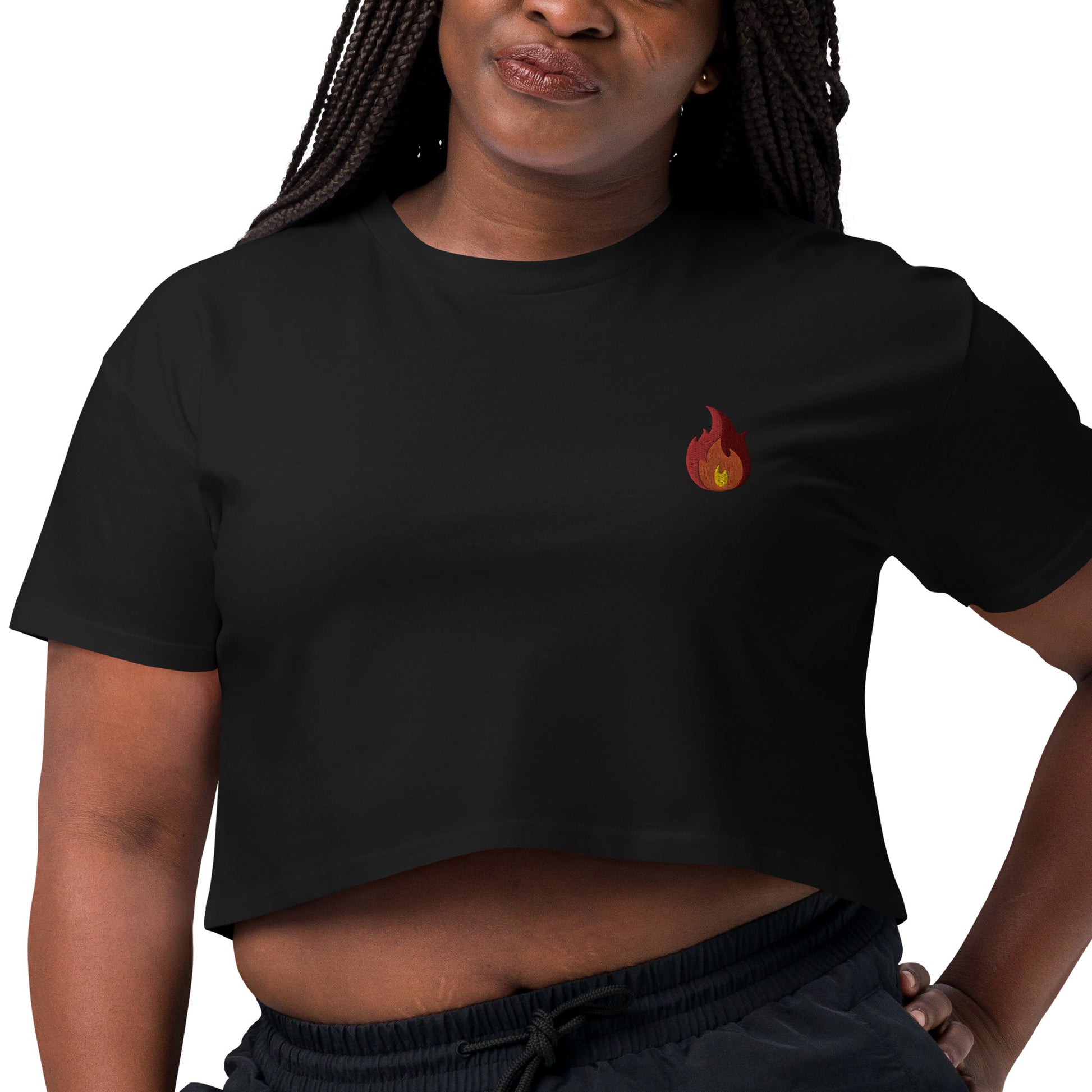 A female model wearing a relaxed black crop top features a modest crop and subtle fire emoji embroidered design, adding a touch of mischief to your look—a playful celebration of gay culture! Made from 100% combed cotton. Available in Extra Small, Small, Medium, Large, Extra Large.