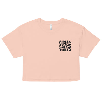 A relaxed, modest pale pink crop top features a subtle black embroidery featuring the quote: girls gays & they's. Adding a touch of LGBTQ+ to your look—a playful celebration of queer culture! Made from 100% combed cotton. Available in Extra Small, Small, Medium, Large, Extra Large.