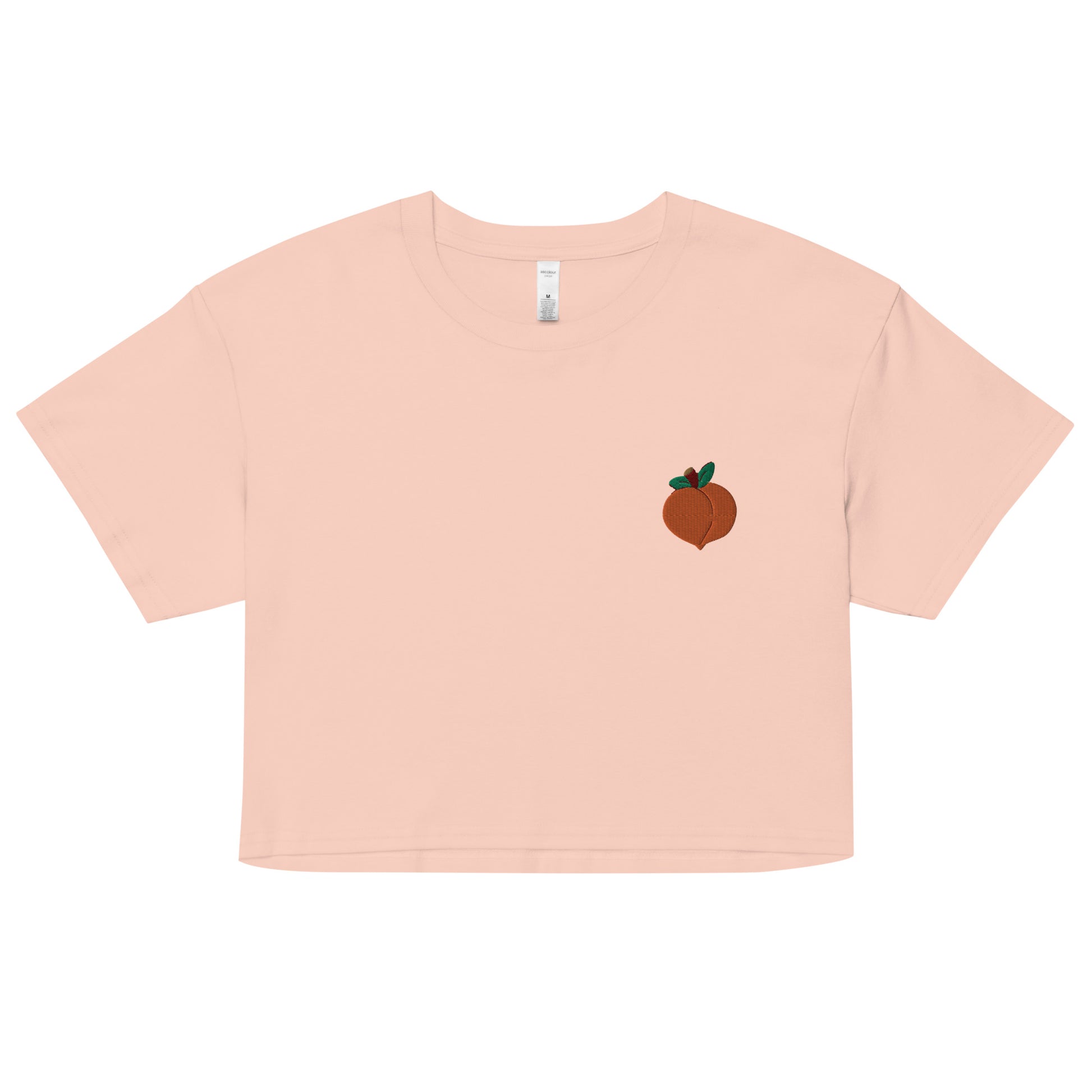 A relaxed, modest pale pink crop top features a subtle peach emoji embroidery. Adding a touch of mischief to your look—a playful celebration of lgbtq culture! Made from 100% combed cotton. Available in Extra Small, Small, Medium, Large, Extra Large.