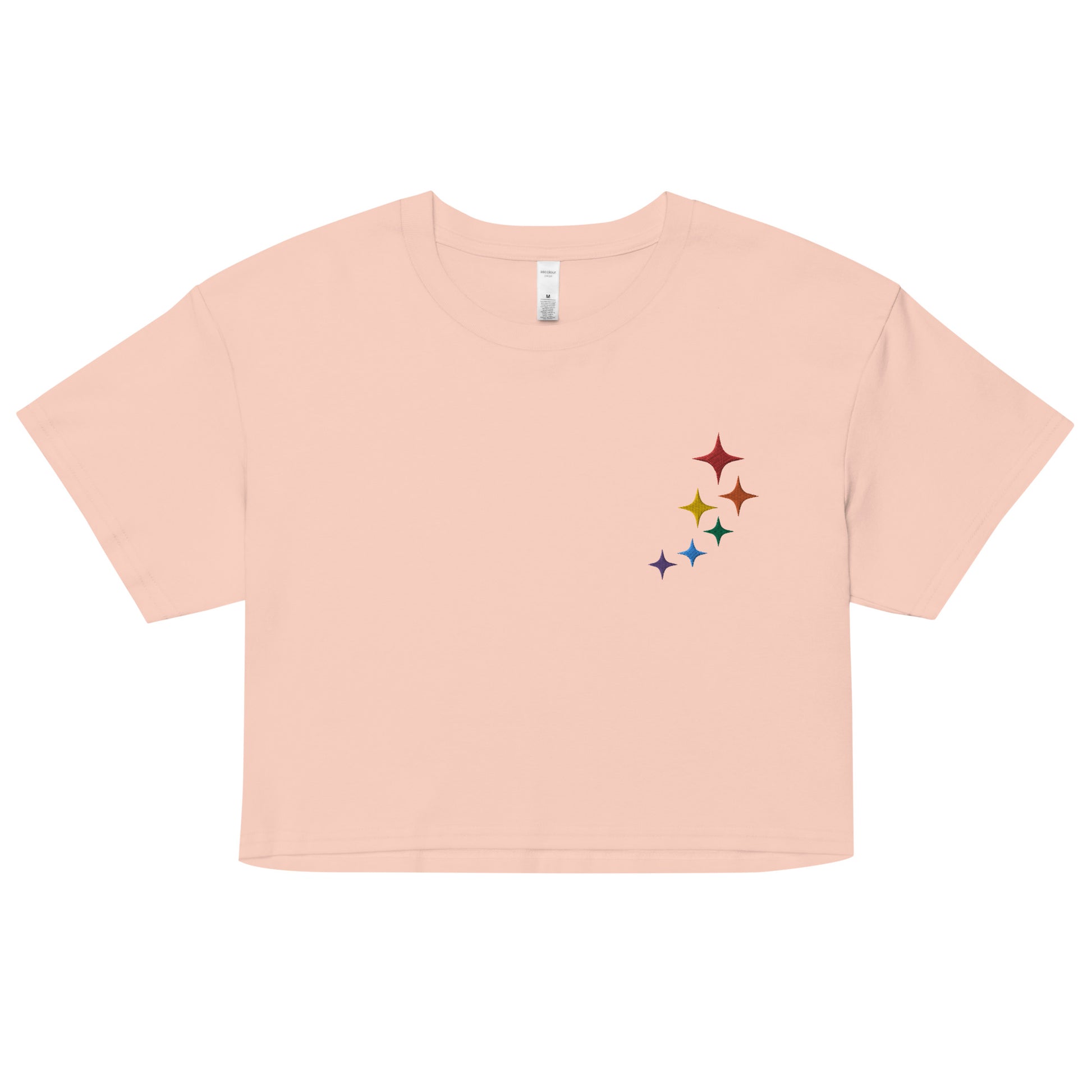 A relaxed, modest pale pink crop top features a subtle rainbow stars embroidery. Adding a touch of rainbow to your look—a playful celebration of lgbtq culture! Made from 100% combed cotton. Available in Extra Small, Small, Medium, Large, Extra Large.
