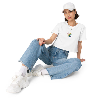 A female model wearing a relaxed, modest white crop top features a subtle rainbow mark embroidery. Adding a touch of rainbow to your look—a playful celebration of lgbtq culture! Made from 100% combed cotton. Available in Extra Small, Small, Medium, Large, Extra Large.